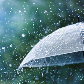 Transparent umbrella under rain against water drops splash background. Rainy weather concept.